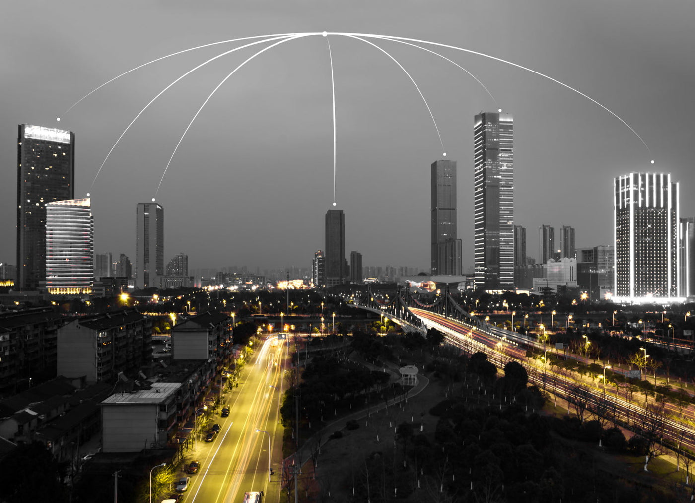 Cityscape with modern skyscrapers at night, illuminated roads, and network signal lines.