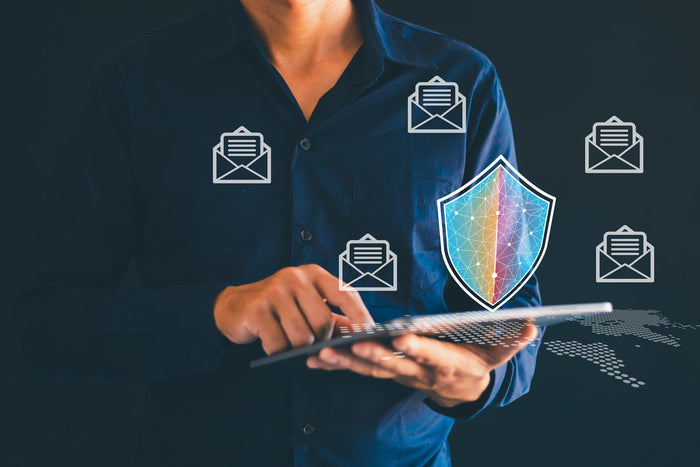 Person using a laptop with security icons and a shield graphic on a dark background