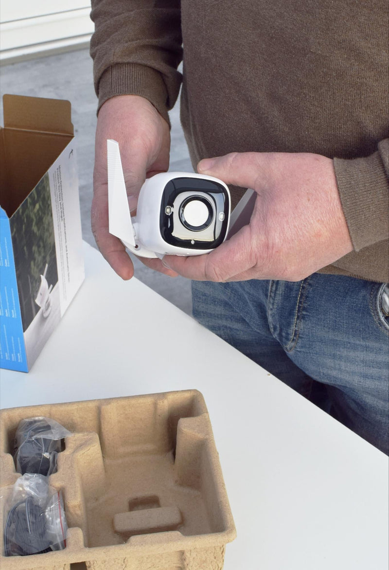 Person holding a security camera with packaging materials in the background