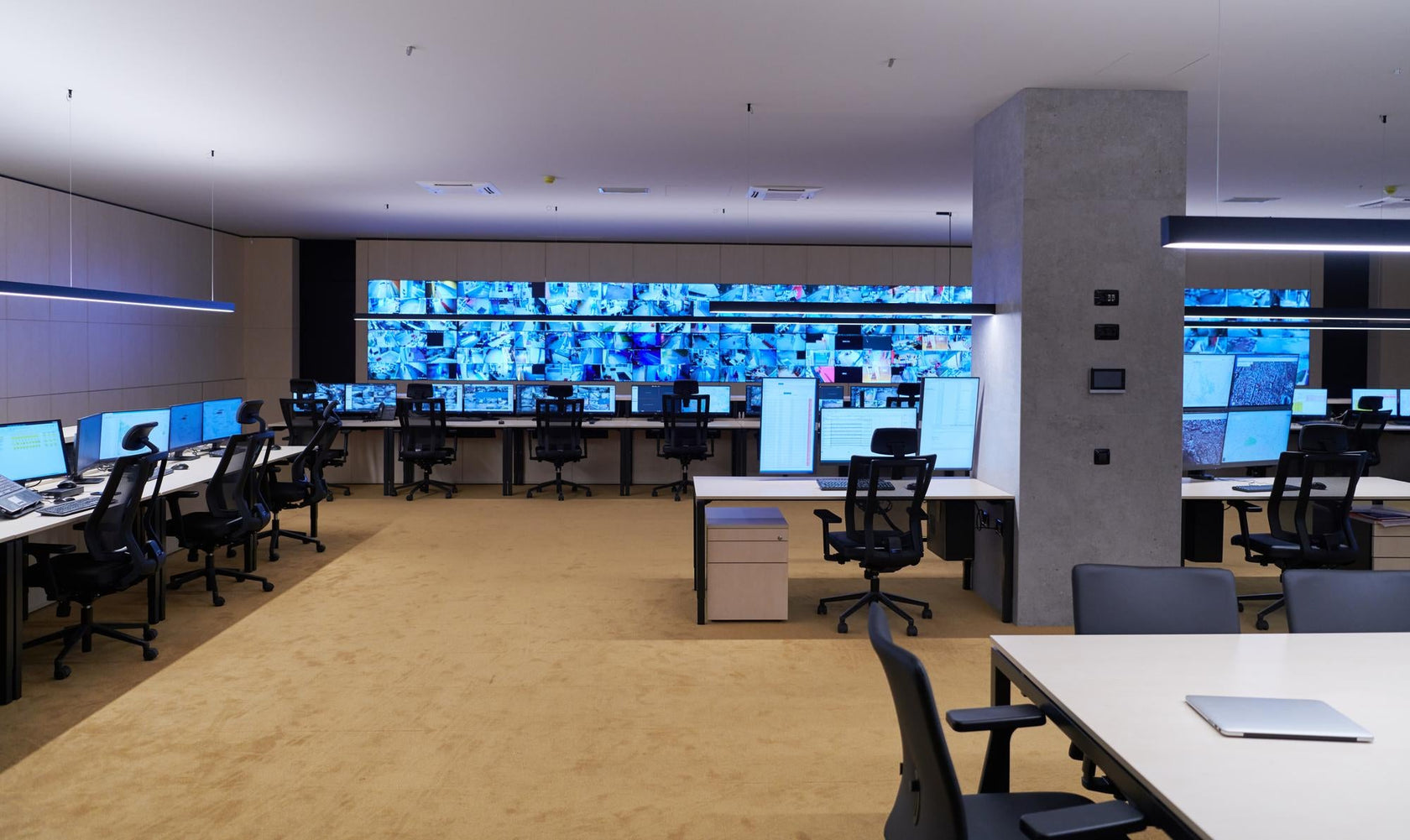 Control room with multiple monitors and desks