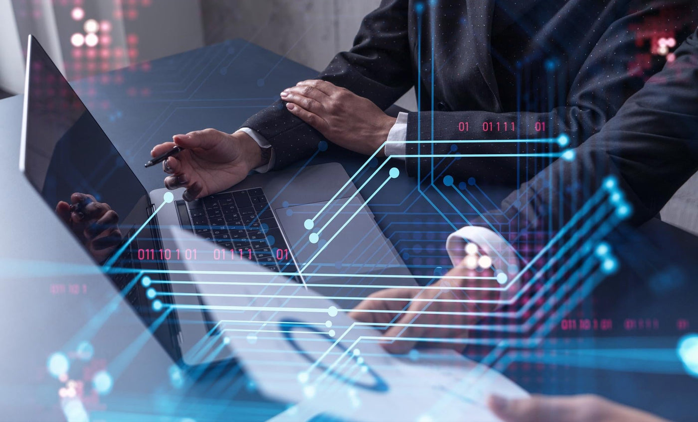 Two people working on laptops with digital elements and code overlay